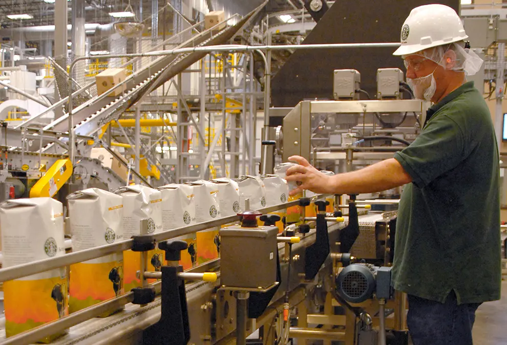 A factory worker reviews bags of Starbucks coffee beans